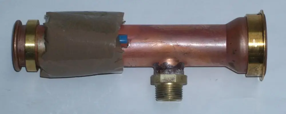 Kupfer-Wasserrohr mit goldenen Muffenanschlüssen und einem seitlichen Anschluss. Vorne teilweise mit braunem Tape umwickelt. Geeignet für DAIKIN-Anlagen.